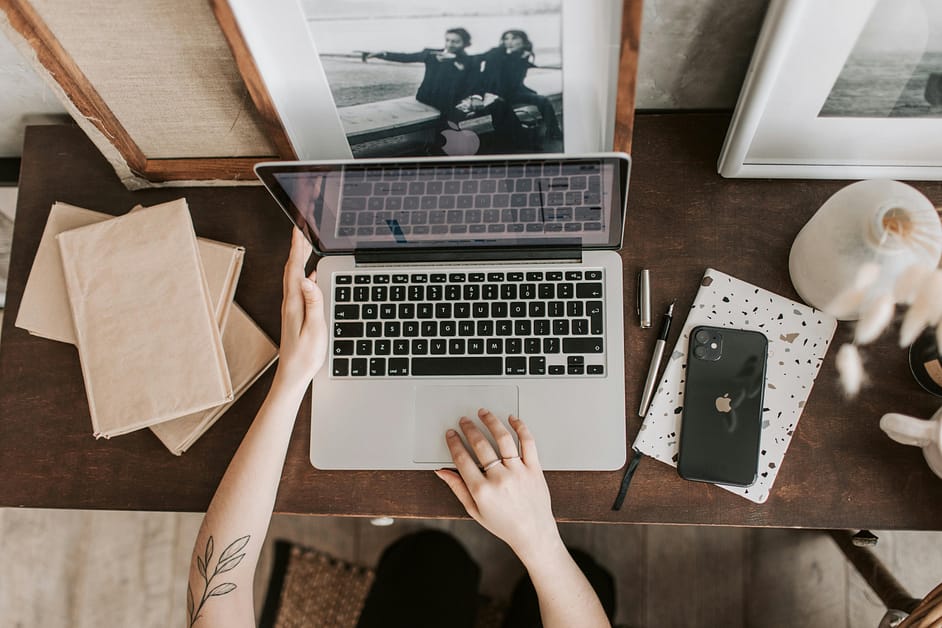 A person using a laptop to complete their taxes on a wooden desk.